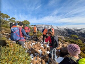 Hero image-elementor-io-optimized | Park Trek Walkers on the white sand of the Bay of Fires with orange lichen-covered granite boulders, Tasmania